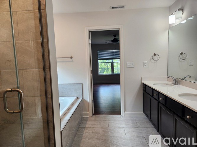 A bathroom with a glass shower door, a bathtub, a sink, and a mirror.