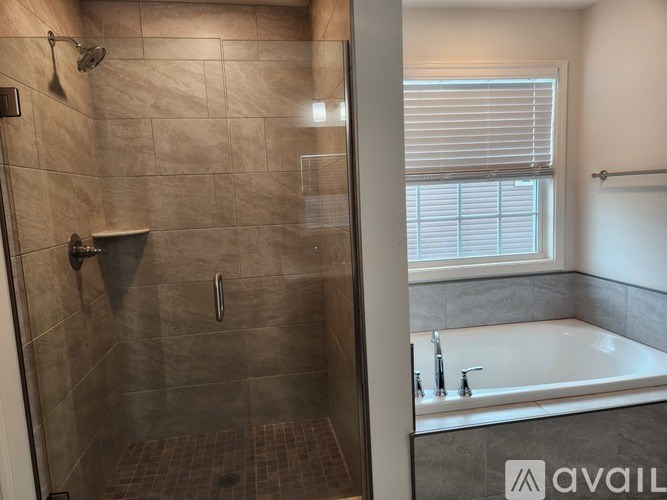 A bathroom with a tiled shower and a bathtub with a window.