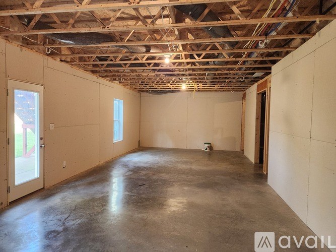 A large empty room with wooden beams on the ceiling and a door on the right side.