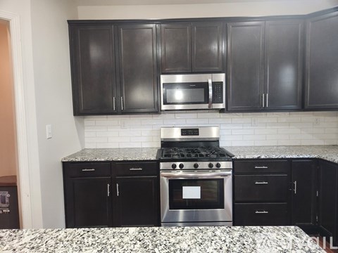 A kitchen with black cabinets and a stove top oven.