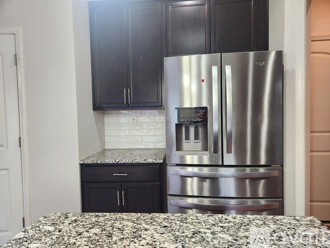 A kitchen with a stainless steel refrigerator and black cabinets.