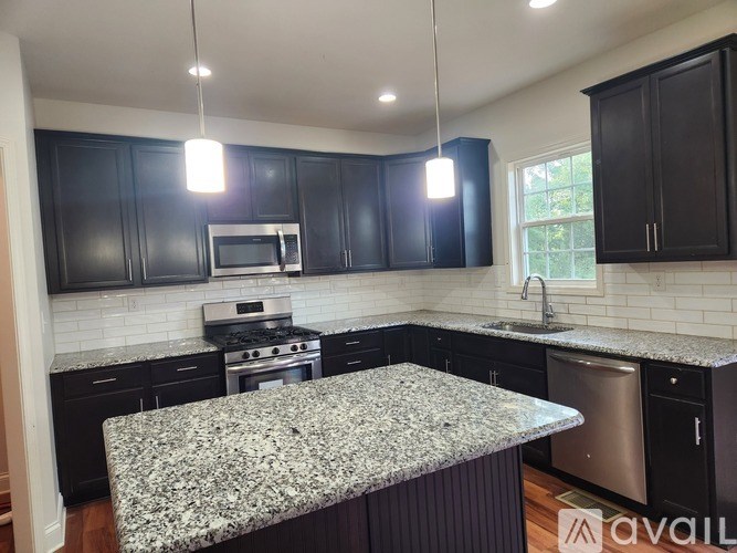 A kitchen with black cabinets and a granite countertop.