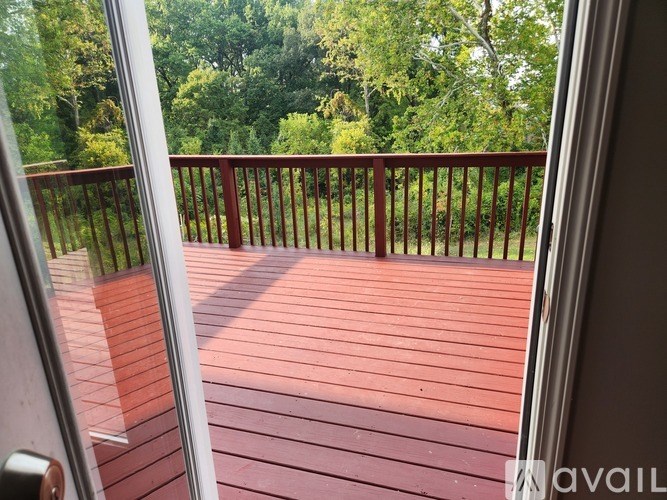 A wooden deck with a railing and trees in the background.