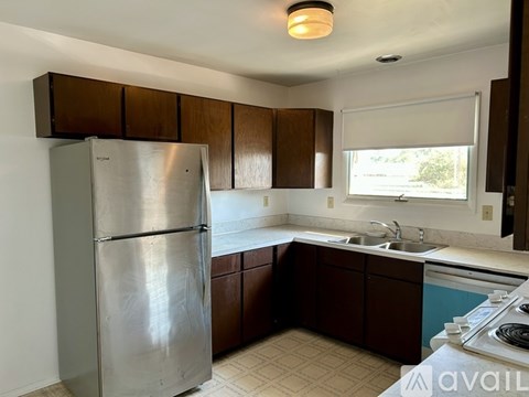 A kitchen with a stainless steel refrigerator and brown cabinets.