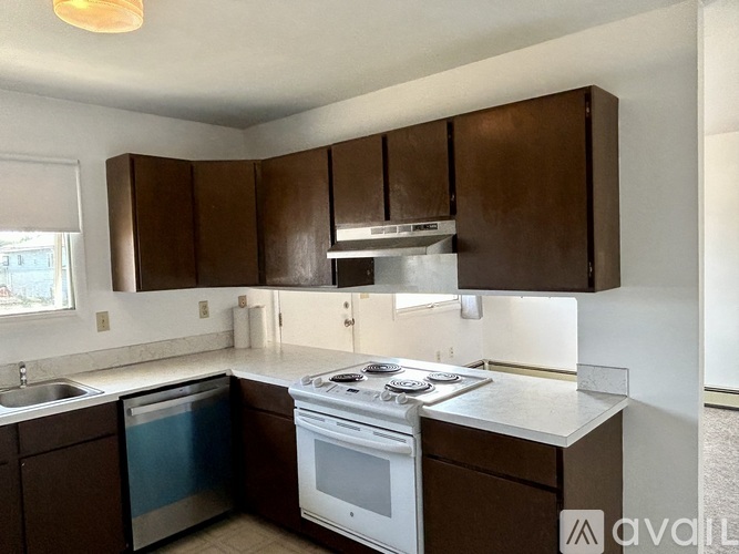 A kitchen with brown cabinets and a white stove top oven.