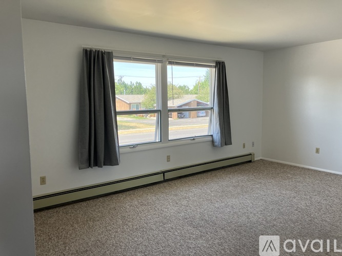 A room with a carpeted floor, a window with a view of a parking lot and a building, and a wall with a logo that says "AVAIL".