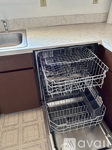 A kitchen with a sink and a dishwasher full of dishes.