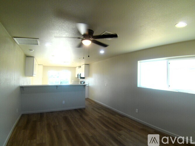 A room with a ceiling fan and wooden flooring.