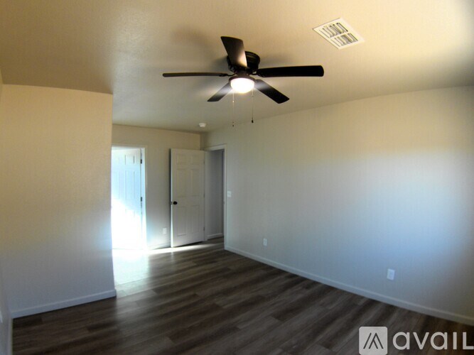 A room with a ceiling fan and wooden flooring.