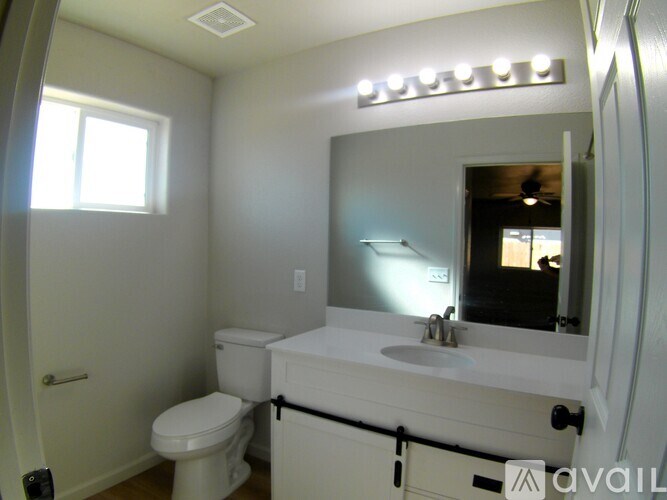 A bathroom with a toilet, sink and mirror.