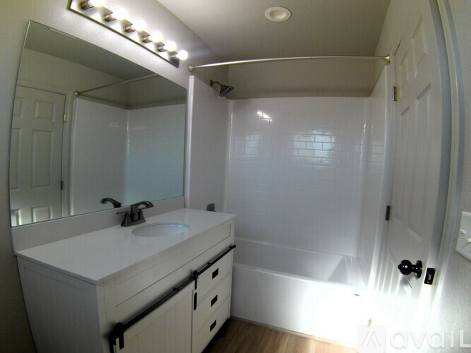 A bathroom with a white sink and a mirror with lights on it.