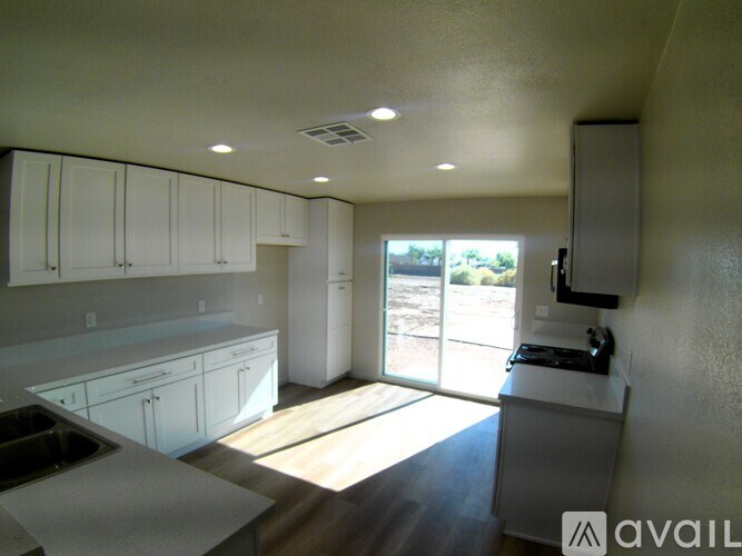 A kitchen with white cabinets and a window overlooking a backyard.