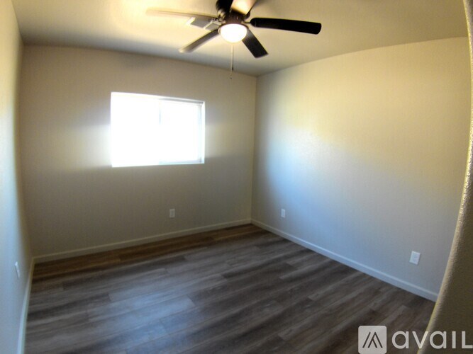 A room with a ceiling fan and a window letting in light.