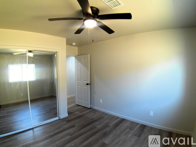 A room with a ceiling fan and a door leading to a hallway.