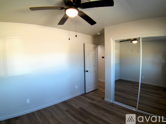 A room with a ceiling fan and a mirror on the wall.