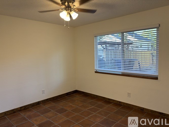 A room with a ceiling fan and a window with blinds.