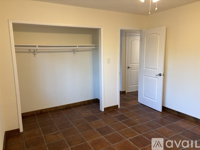 A room with a door and a closet with a shelf.