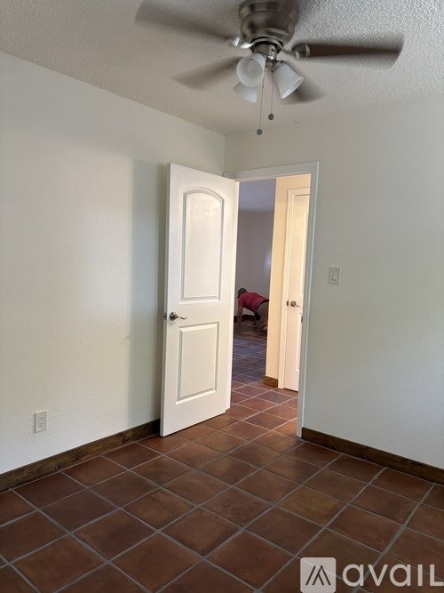 A room with a ceiling fan and tile flooring.