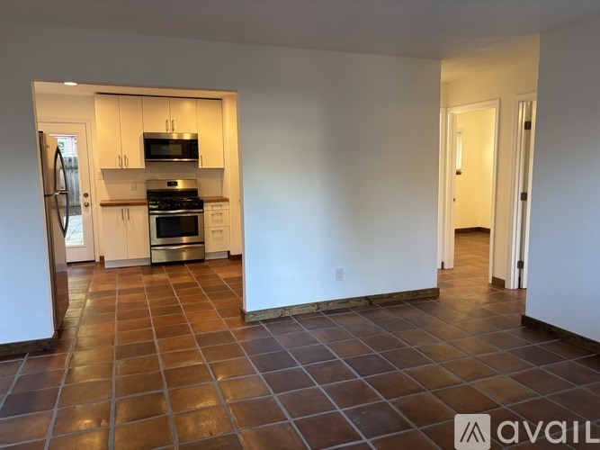 A kitchen with tile flooring and a refrigerator.