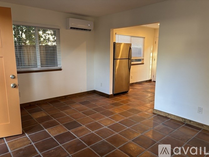 A kitchen with a tile floor and a refrigerator.