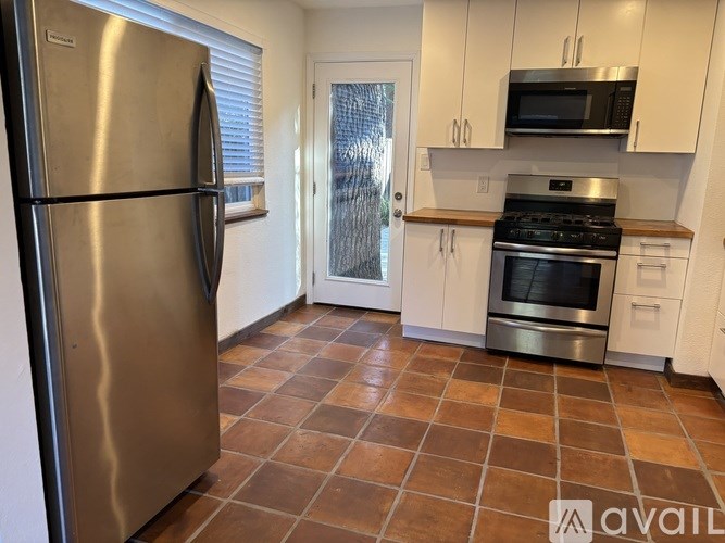 A kitchen with a refrigerator, microwave, oven, and cabinets.