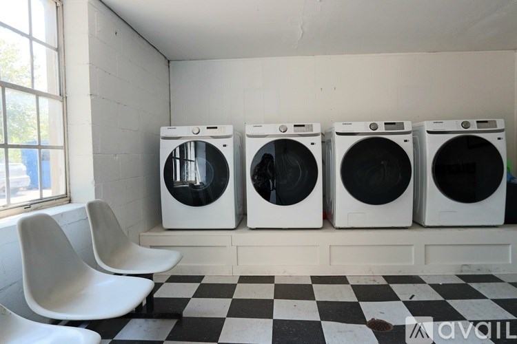Three washing machines are lined up in a laundry room.