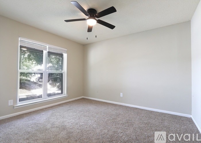 A room with a ceiling fan and a window showing an outdoor view.