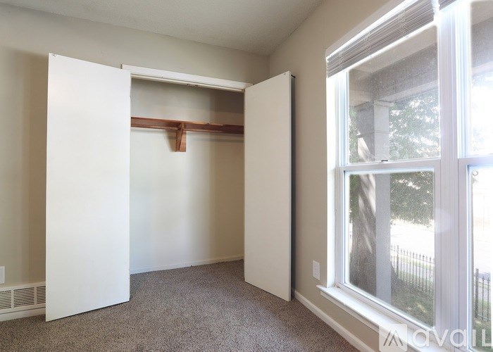 A room with a white door and a window showing trees outside.