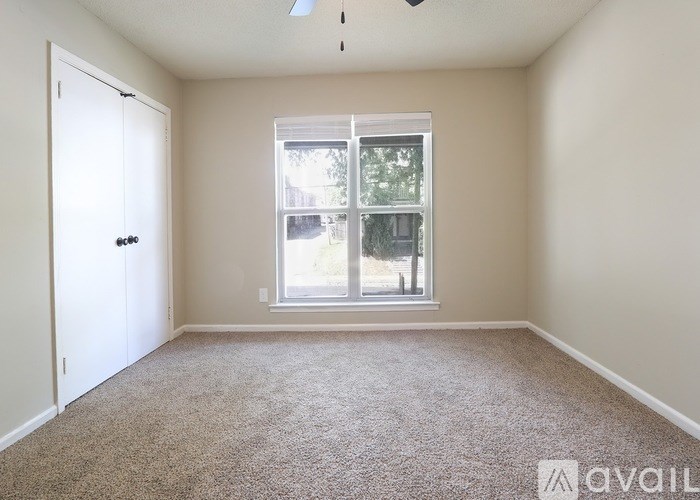 A room with a carpeted floor, a window, and a door.