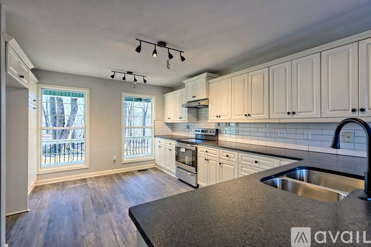 A kitchen with white cabinets and a black countertop.