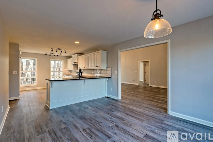 A modern kitchen with white cabinets and a wooden floor.