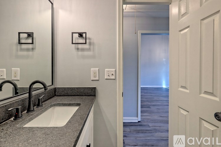 A bathroom with a sink, mirror, and a door.