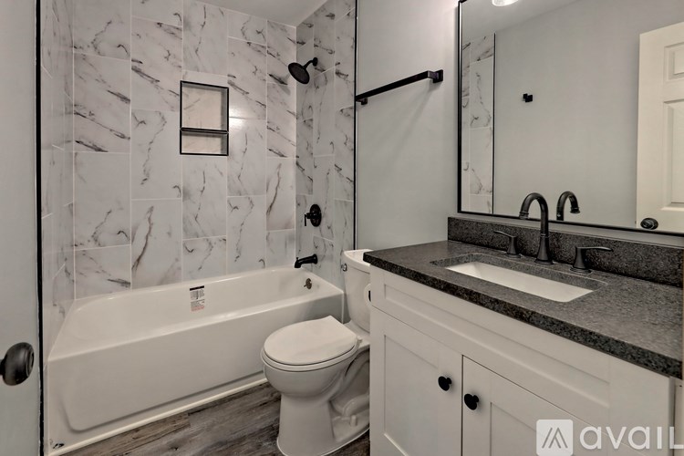 A bathroom with a marble wall and a white bathtub.