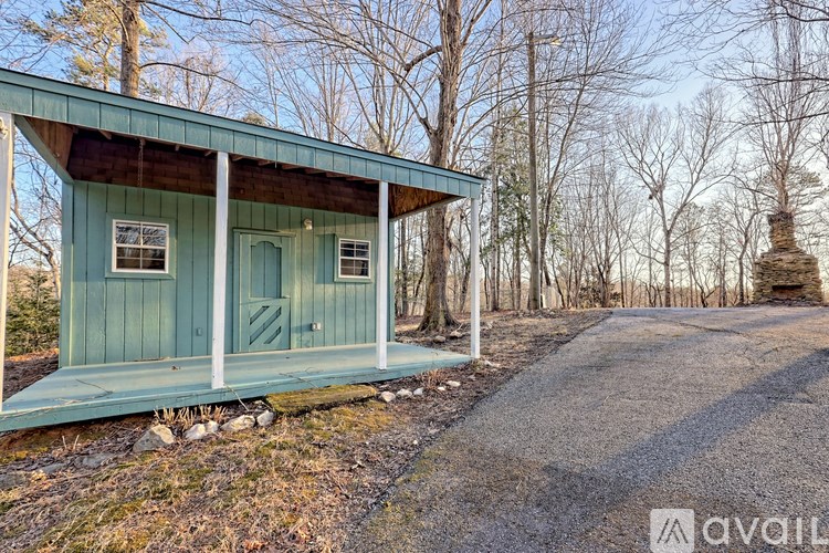 A small house with a porch and a gravel driveway in front of it.