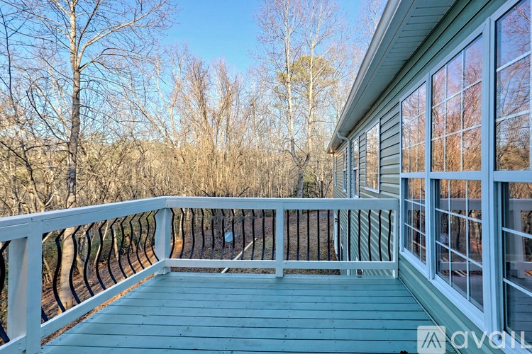 A deck with a railing and a view of trees.