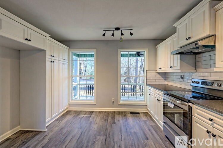 A kitchen with white cabinets and a wooden floor.