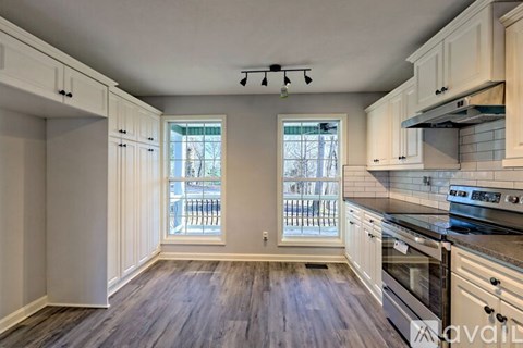A kitchen with white cabinets and a wooden floor.