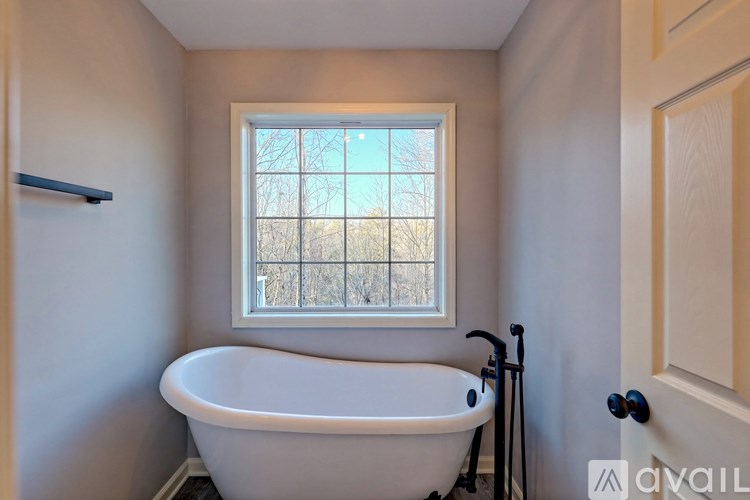 A bathroom with a bathtub, window, and a door.