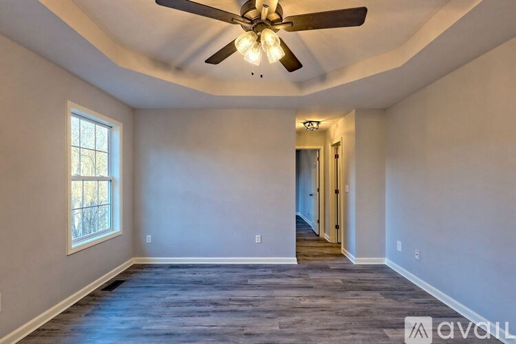 A spacious room with a ceiling fan and wooden flooring.