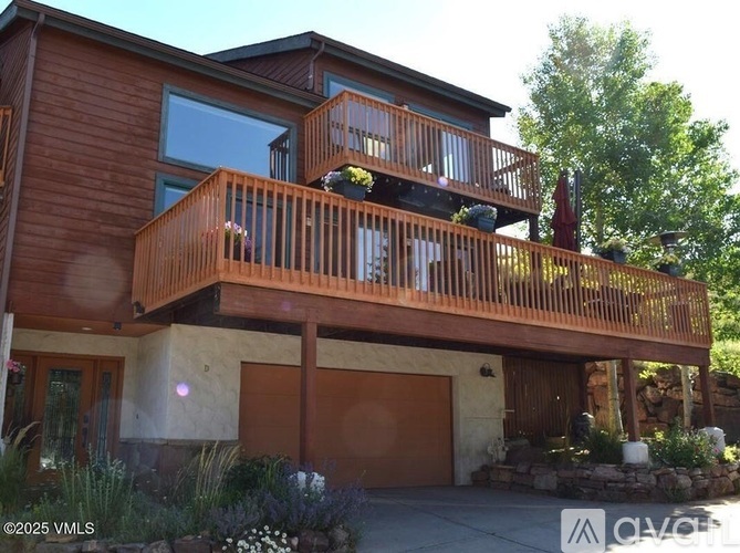 A modern house with a large deck and a stone wall.