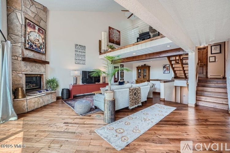 A living room with a stone fireplace and a rug on the floor.
