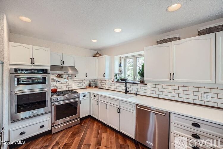 A kitchen with white cabinets and a wooden floor.