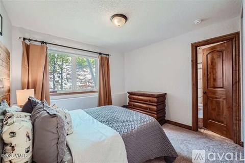 A bedroom with a bed, pillows, and a window with curtains.