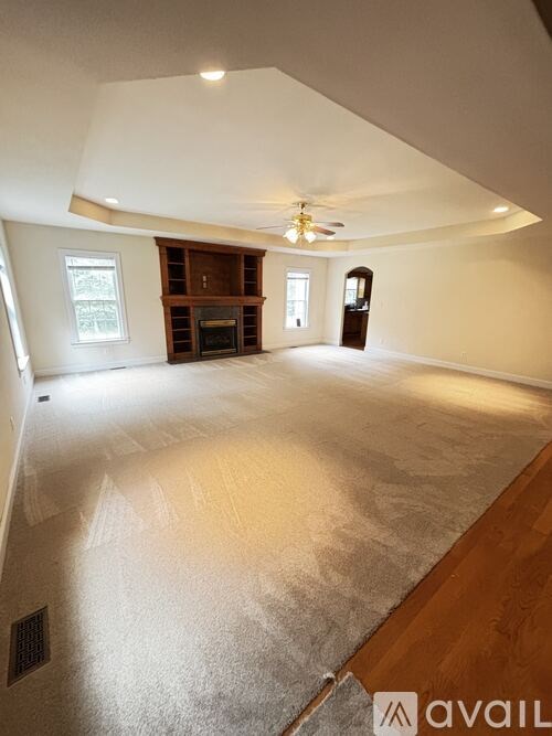 A spacious living room with a fireplace and a ceiling fan.