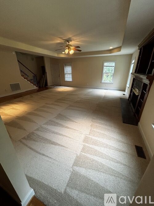 A spacious room with a carpeted floor and a ceiling fan.