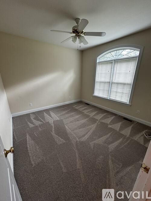 A room with a carpeted floor and a ceiling fan.