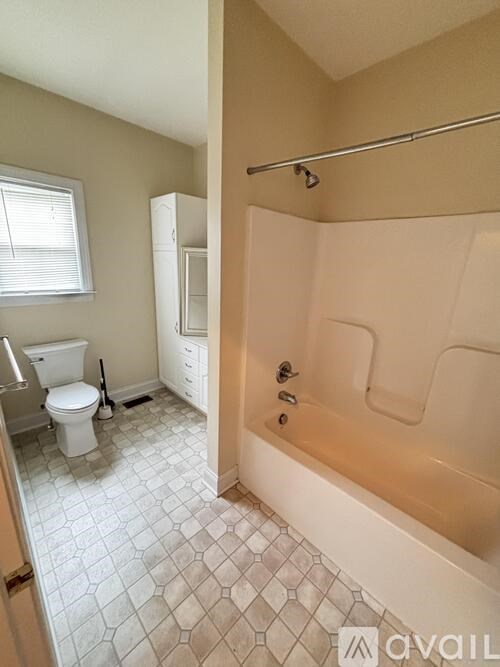 A bathroom with a toilet, a tub, and a towel rack.
