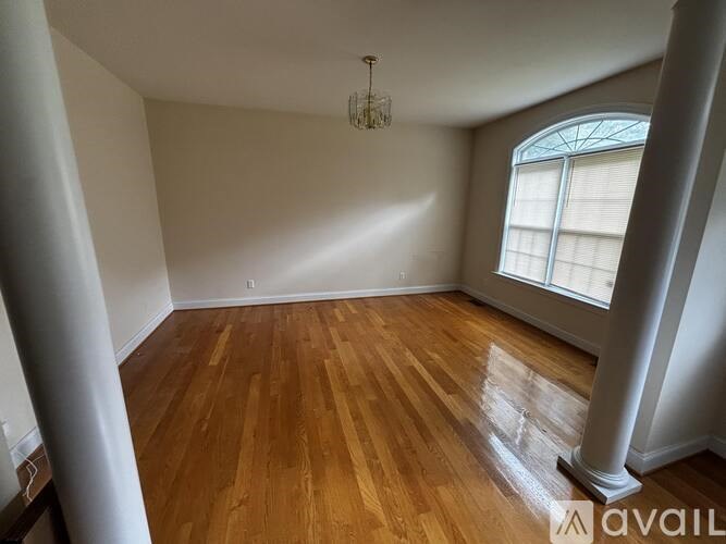 A room with wooden flooring and a chandelier hanging from the ceiling.