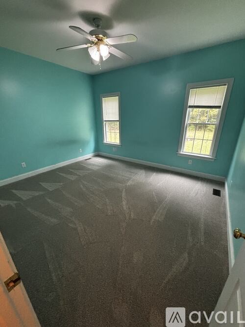 A room with a ceiling fan and two windows.