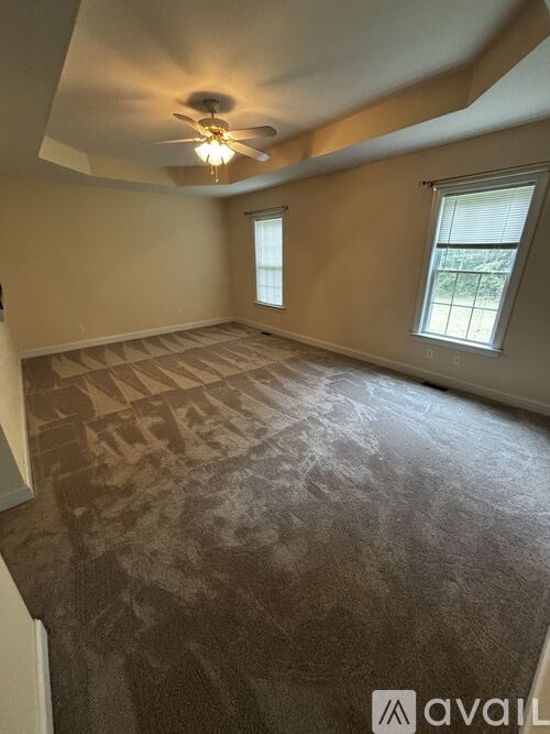 A room with a carpeted floor and a ceiling fan.